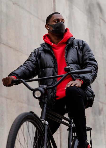 Uomo che indossa una maschera e in sella alla sua bicicletta