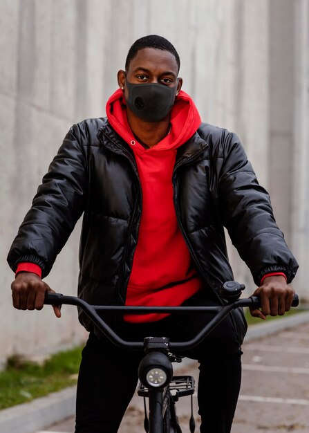 Uomo che indossa una maschera e tiene la sua bicicletta