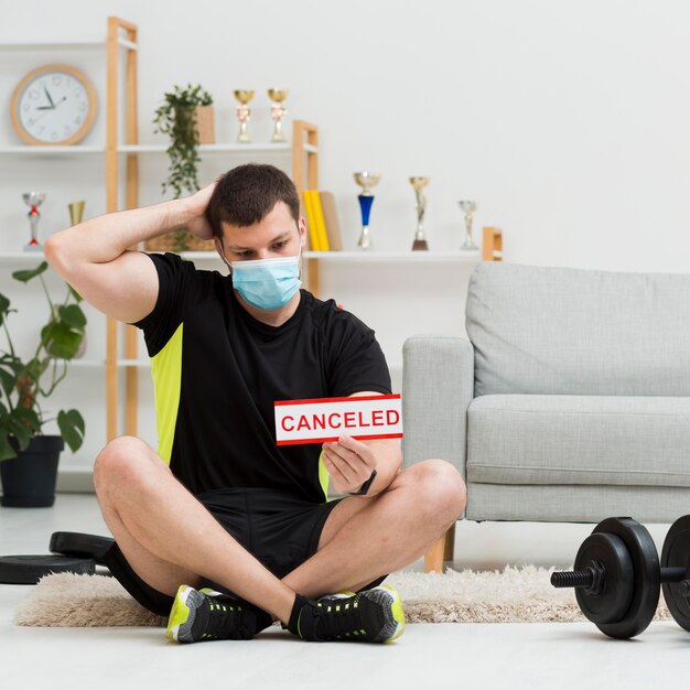 Uomo che indossa una maschera medica mentre indossa abiti sportivi a casa