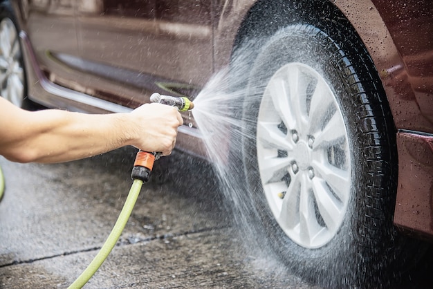 Uomo che lava auto usando shampoo e acqua