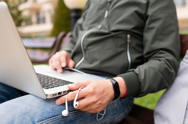 Uomo che lavora al computer portatile all'esterno con le cuffie