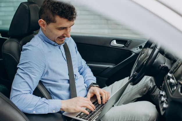 Uomo che lavora al computer portatile all'interno della sua auto