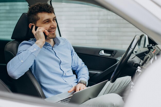 Uomo che lavora al computer portatile all'interno della sua auto