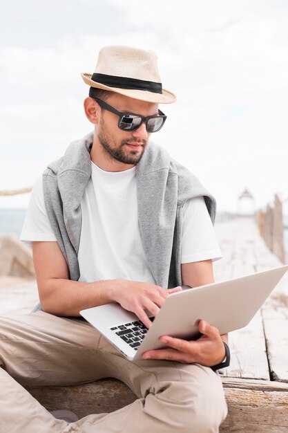 Uomo che lavora al computer portatile in spiaggia