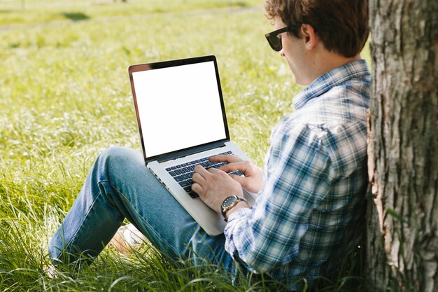 Uomo che lavora al computer portatile nel parco