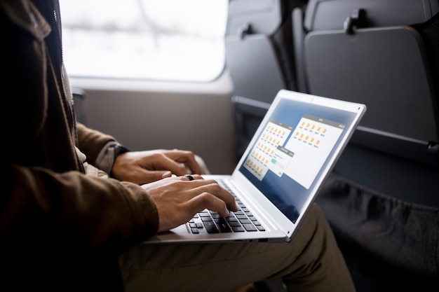 Uomo che lavora al suo computer portatile mentre viaggia in treno