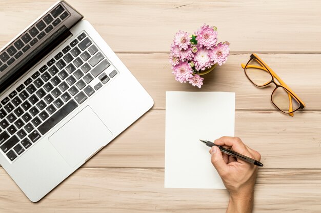 Uomo che lavora al tavolo con foglio di carta vuoto e notebook