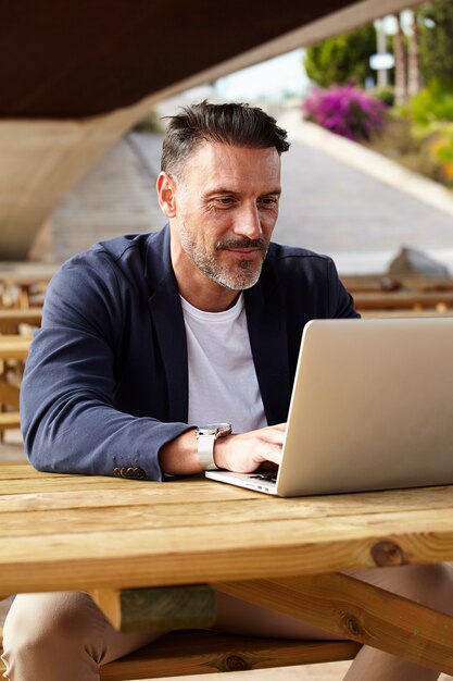 Uomo che lavora con il suo computer all'aperto