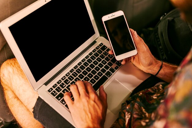 Uomo che lavora con laptop e smartphone