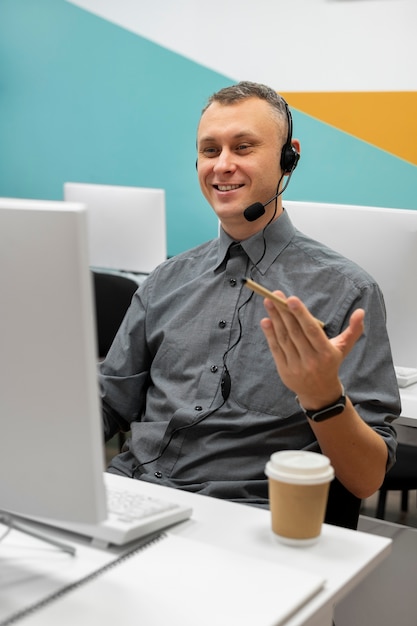 Uomo che lavora in un call center con cuffie e computer