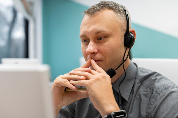 Uomo che lavora in un call center con cuffie e computer