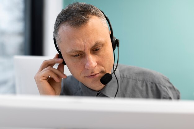 Uomo che lavora in un call center con cuffie e computer