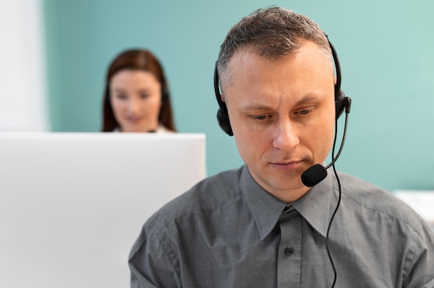 Uomo che lavora in un call center con cuffie e computer