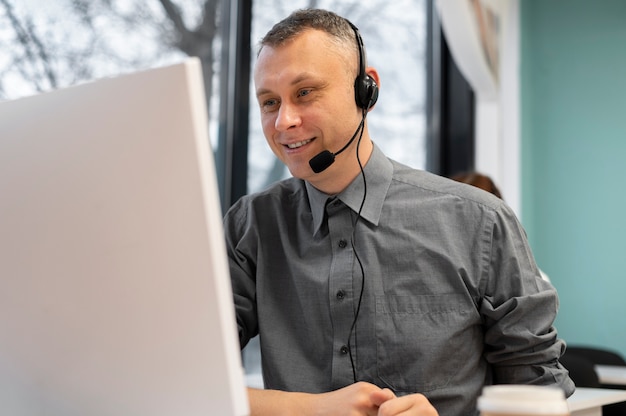 Uomo che lavora in un call center con cuffie e computer