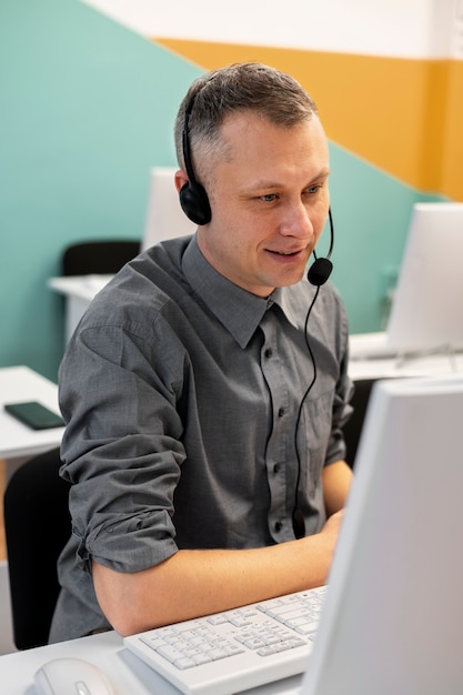 Uomo che lavora in un call center con cuffie e computer