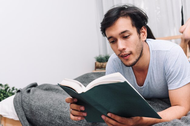 Uomo che legge un libro nella vita universitaria della camera da letto