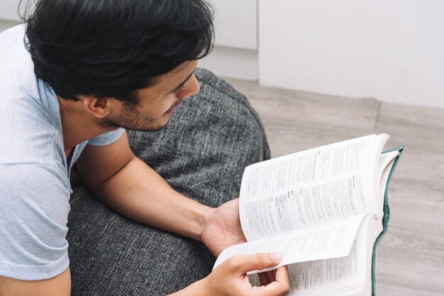 Uomo che legge un libro nella vita universitaria della camera da letto