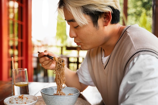 Uomo che mangia con le bacchette vista laterale