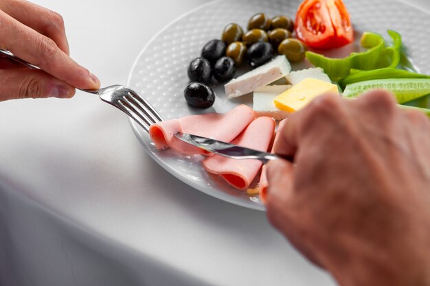 Uomo che mangia prima colazione che mangia salsiccia. Veduta dall'alto.