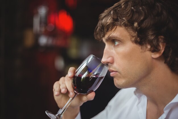 Uomo che mangia un bicchiere di vino rosso