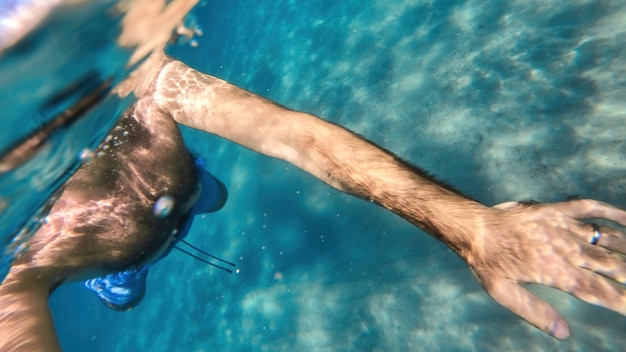 Uomo che nuota nell'acqua del Mar Mediterraneo