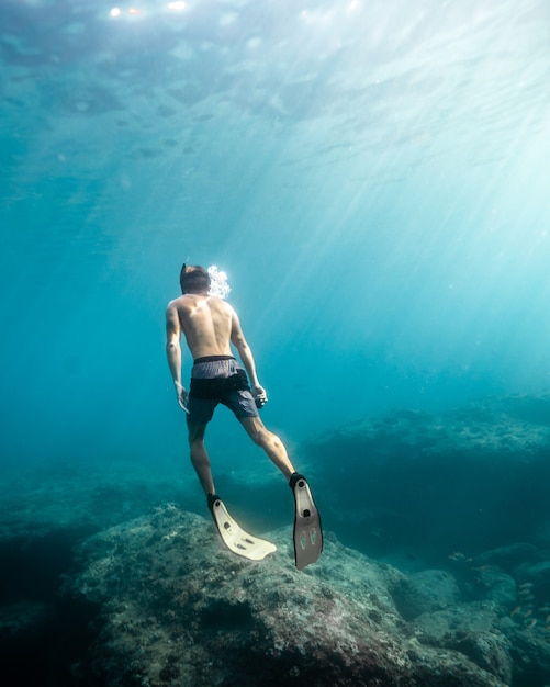 Uomo che nuota sott'acqua durante una giornata di sole