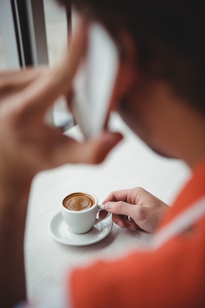 Uomo che parla al telefono cellulare mentre beve il caffè