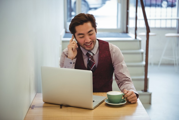 Uomo che parla al telefono cellulare mentre beve il caffè