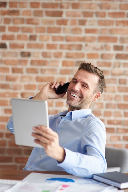 Uomo che parla al telefono e navigazione tablet digitale