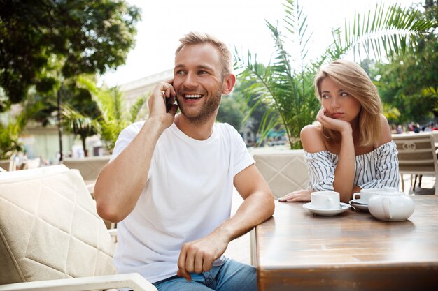 Uomo che parla al telefono mentre la sua ragazza è annoiata.