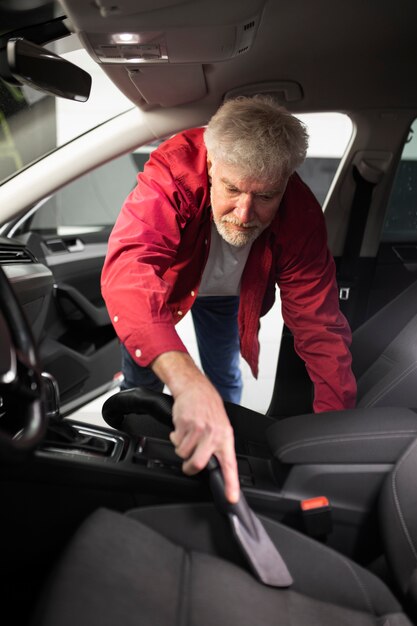 Uomo che passa l'aspirapolvere sui sedili dell'auto