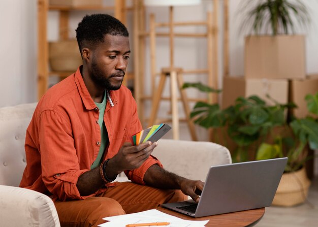 Uomo che pianifica sulla ristrutturazione della casa utilizzando laptop e tavolozza dei colori