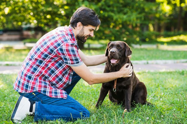 Uomo che picchietta il suo cane nel parco