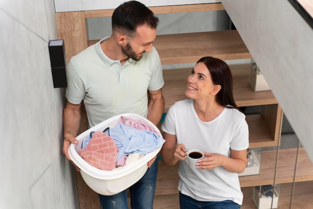 Uomo che porta un mucchio di vestiti sporchi nel cestino