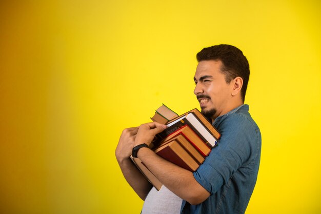 Uomo che porta una pila di libri pesanti.