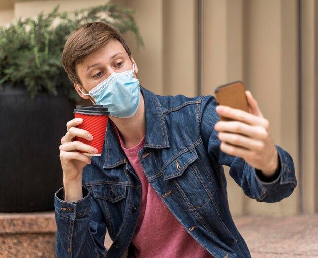 Uomo che prende un selfie con la sua maschera facciale