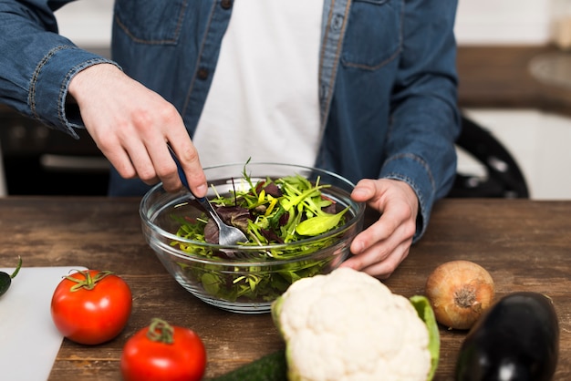 Uomo che prepara insalata in cucina