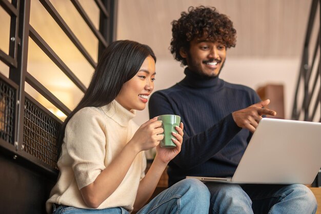 Uomo che punta allo schermo e donna che guarda il computer portatile