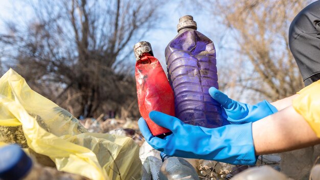 Uomo che raccoglie bottiglie di plastica sparse da terra