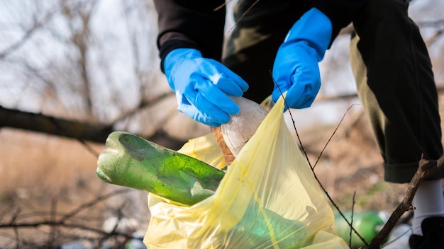 Uomo che raccoglie bottiglie di plastica sparse da terra