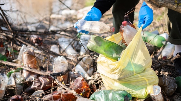 Uomo che raccoglie bottiglie di plastica sparse da terra