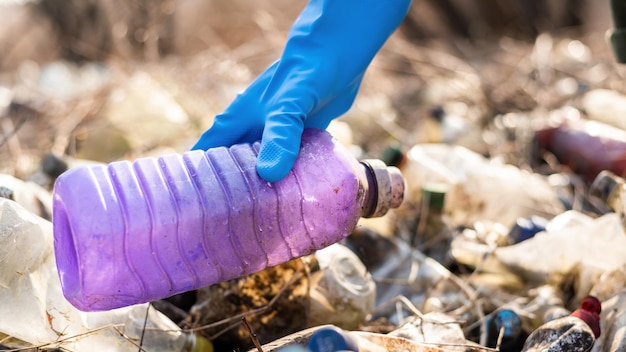 Uomo che raccoglie bottiglie di plastica sparse da terra