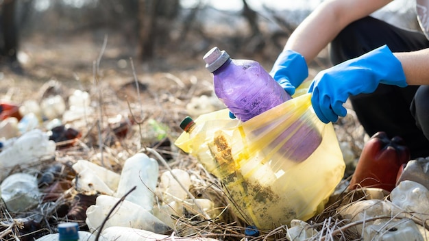 Uomo che raccoglie bottiglie di plastica sparse da terra