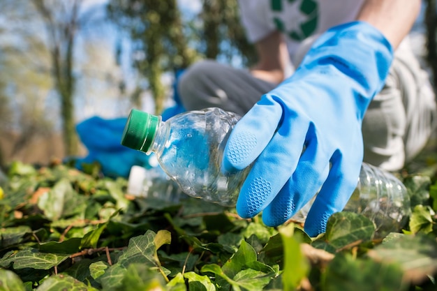 Uomo che raccoglie rifiuti di plastica in un parco inquinato