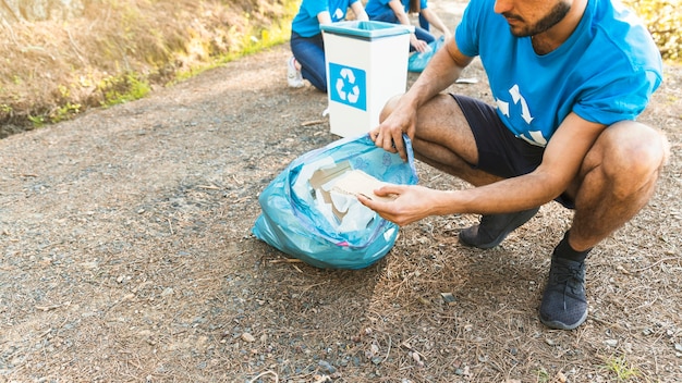 Uomo che raccoglie spazzatura nel sacchetto di plastica