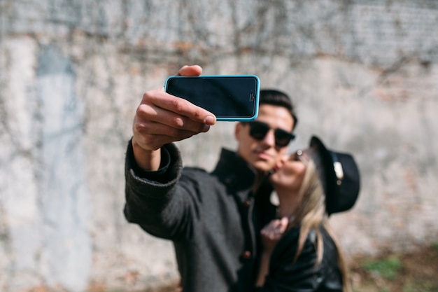 Uomo che riceve un bacio dalla sua fidanzata mentre si scatta una foto