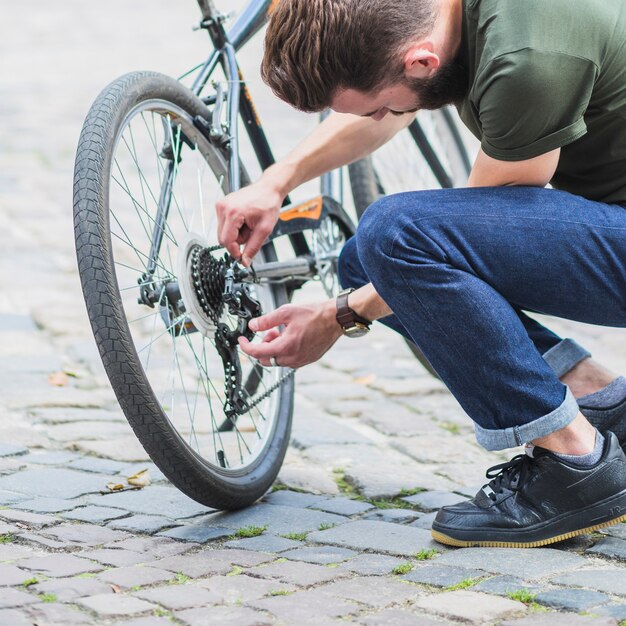 Uomo che ripara la sua bicicletta in strada