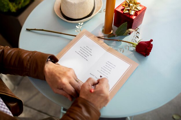 Uomo che scrive in un biglietto di auguri mentre è seduto a un tavolo