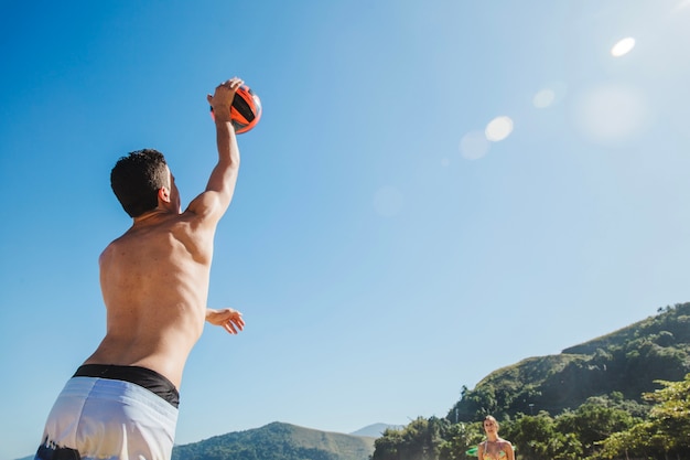 Uomo che serve pallavolo in una giornata di sole