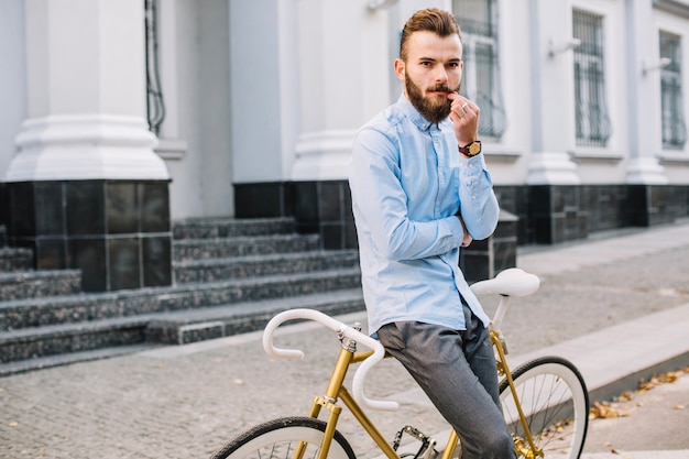 Uomo che si appoggia sulla bicicletta e toccando i baffi